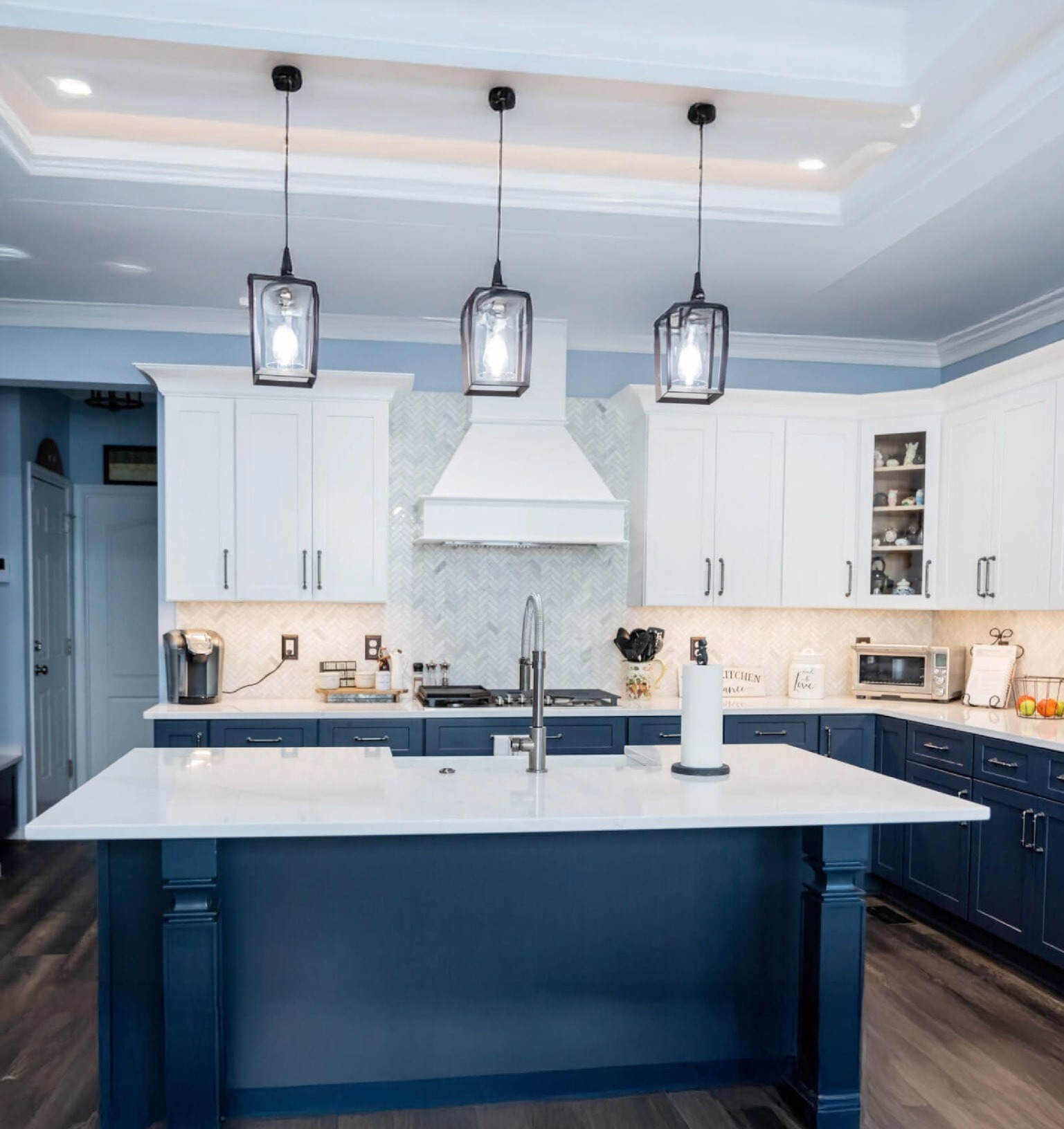 Navy island kitchen with a pale stone countertop and herringbone backsplash installed by Absolute Stone Design TN